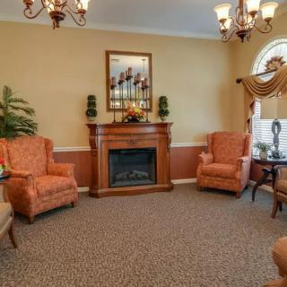 A cozy living room with a fireplace, armchairs, and elegant lighting.