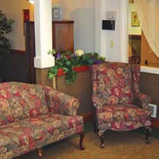 A cozy living room area with floral patterned furniture, including a sofa and armchair.