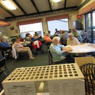 A group of elderly people socializing and playing bingo in a community center.