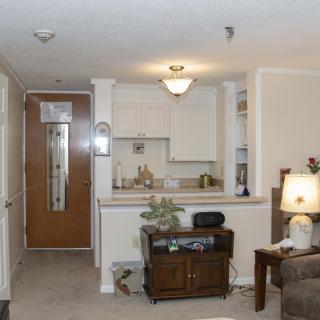 A cozy apartment interior featuring a small kitchen and living area with traditional furnishings.