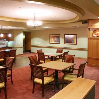 An interior view of a neatly arranged dining area with tables and chairs, featuring warm lighting and decor.