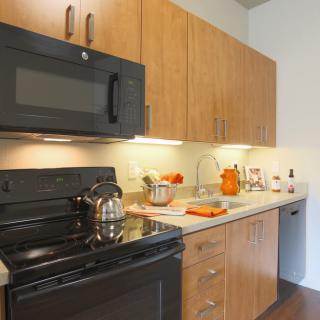 A modern kitchen with wooden cabinets and black appliances.