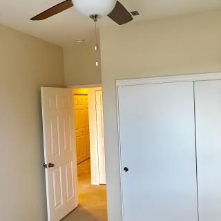 An empty bedroom with a ceiling fan and a closed closet door.