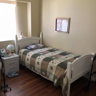 A cozy bedroom with a single bed, a quilt, and a nightstand featuring a globe and lamp.