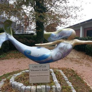 A beautiful mermaid sculpture gracefully swimming, surrounded by nature.
