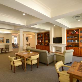 A spacious and well-lit living room with multiple seating areas, bookshelves, and a fireplace.