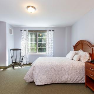 A cozy bedroom with a bed, rocking chair, and wooden furniture.