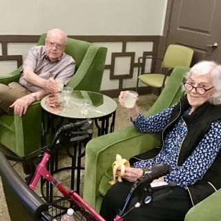 Two senior individuals relaxing in a comfortable seating area.