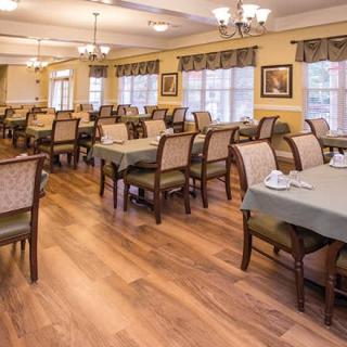 An elegant dining room with neatly arranged tables and chairs on a wooden floor.