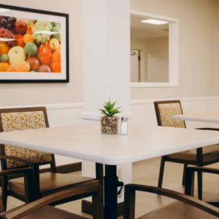 A cozy dining area featuring a table with chairs and a small potted plant, complemented by wall art depicting fruits.