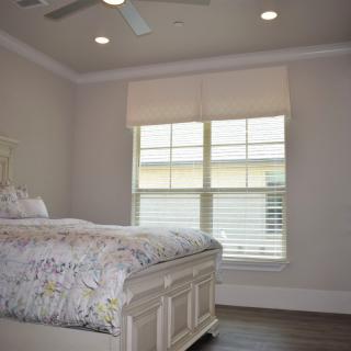 A cozy bedroom with a bed, window blinds, and a ceiling fan.