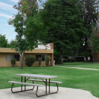 A small park area with a picnic table, trees, and a nearby building.
