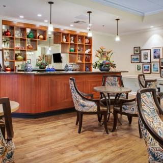 A cozy cafe interior featuring a wooden bar counter, stylish chairs, and decorative artwork on the walls.