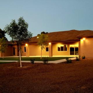 A modern house exterior at dusk with trees and exterior lighting.