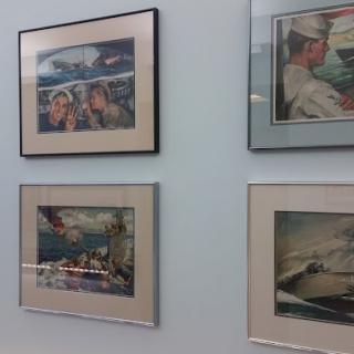 A collection of framed vintage-style aviation paintings featuring military pilots on display.