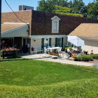 A charming house with a well-maintained garden and outdoor seating, perfect for enjoying sunny days.