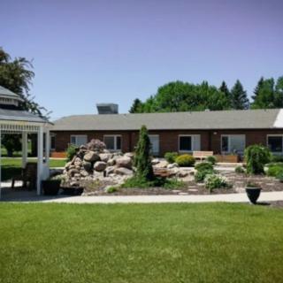 A scenic view of a house with a gazebo, landscaped garden, and lush green lawn on a sunny day.