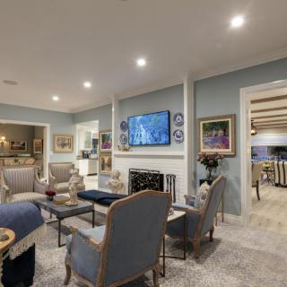 A cozy and elegantly designed living room with a central fireplace, television, and comfortable seating area.