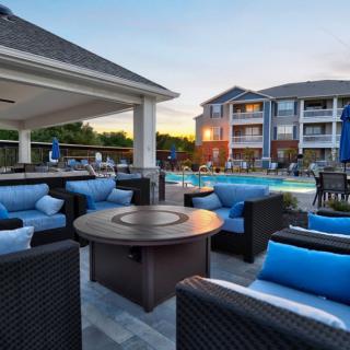 A stylish outdoor seating area by the pool at an apartment complex during sunset.