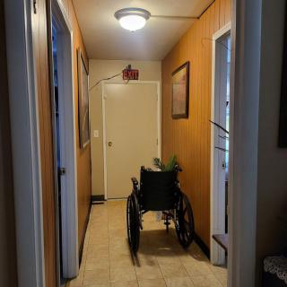 A dimly lit hallway with a wheelchair positioned near the door.