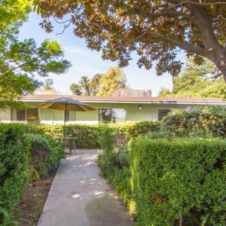 A charming house with a well-maintained garden pathway surrounded by lush greenery.