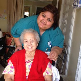A caregiver and an elderly woman smiling together at home.