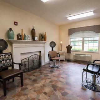 A cozy hair salon with vintage decor and styling chairs arranged around a fireplace.