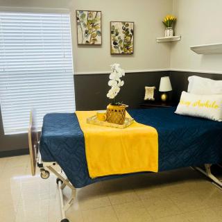 A modern and neatly decorated hospital room with a navy and yellow theme.