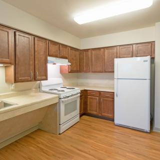 A clean kitchen featuring wooden cabinets, a white refrigerator, and an electric stove.