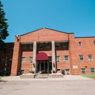 A brick residential building with a red awning over the entrance.