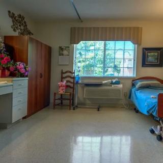 A neatly arranged hospital room featuring a bed, window, and decor.