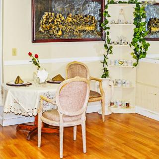 A cozy dining area with a small table, two chairs, decorative plants, and artwork on the walls.
