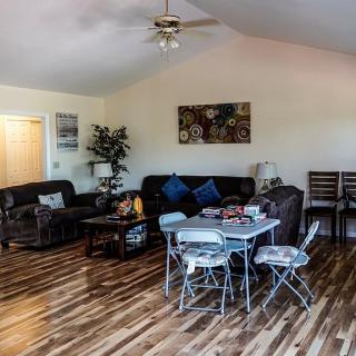 A cozy living room with sofas, a small table, chairs, and wooden flooring.