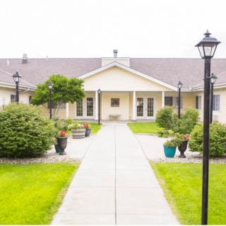 A landscaped pathway leading to a residential building with outdoor lighting.