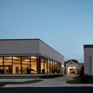 A modern building with large windows illuminated in the evening light.