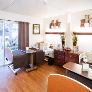 A well-organized and cozy room in a nursing home with essential furniture and bright decor.