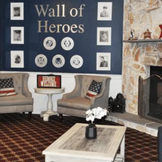 A cozy seating area with a 'Wall of Heroes' displaying portraits, complemented by patriotic decor and a warm fireplace.
