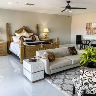A spacious and elegantly decorated bedroom featuring a large bed, sofa, and stylish furniture.