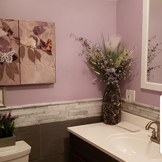 A stylish bathroom with purple walls, featuring floral artwork and a decorative vase on the counter.