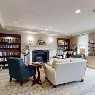 A cozy library space with bookshelves, a fireplace, and comfortable seating.