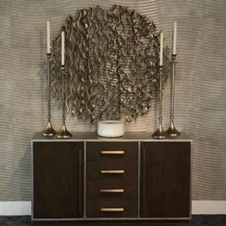 A stylish sideboard adorned with tall candlesticks and a decorative vase, set against textured wall art.