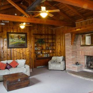 A cozy living room with wooden paneling, a brick fireplace, and comfortable seating.