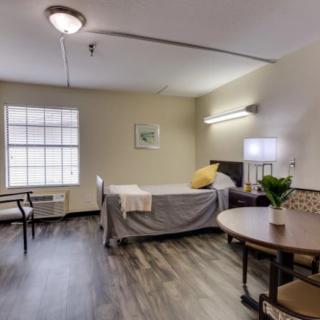 A minimalist bedroom with a single bed, table, and chair.