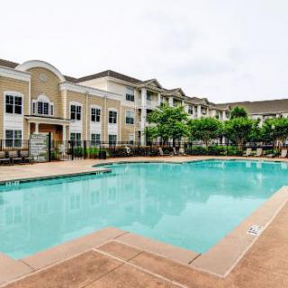 An outdoor swimming pool in front of a large residential apartment complex.