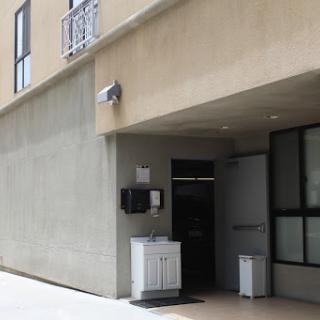 The entrance of a modern building featuring a concrete facade and a security camera.