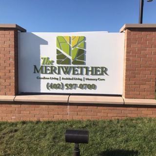 A sign on a brick structure advertising 'The Meriwether' with contact information.
