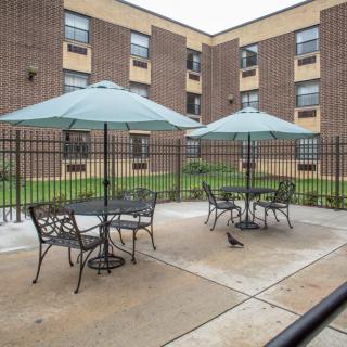 A courtyard with patio furniture and umbrellas surrounded by a brick building.