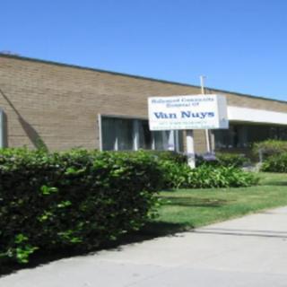 A business building with a sign outside surrounded by greenery.