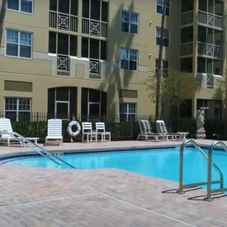 A sunny day at an apartment complex with a swimming pool and lounge chairs.