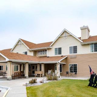 A spacious two-story house with a patio, surrounded by a landscaped backyard.
